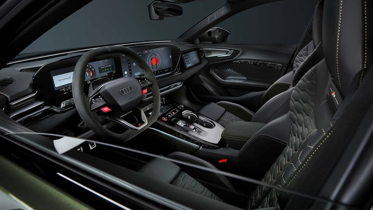 نمای داخلی از زاویه جانبی کابین RS5 با صندلی‌های اسپرت، دو نمایشگر عریض و جزئیات فیبرکربنی