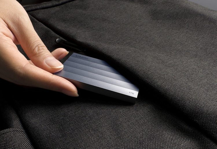 نمای تبلیغاتی از حافظه SSD قابل حمل شیائومی با طراحی فلزی مینیمال و ظرفیت یک ترابایت در پسزمینهای مدرن و تیره