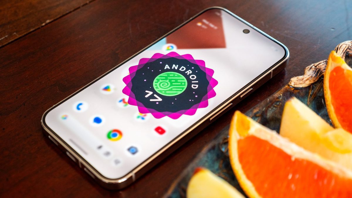 گوشی هوشمند اندرویدی قرارگرفته روی میز چوبی که لوگوی Android 17 با نشان دایرهای سبز و الگوی مداری روی صفحه نمایش آن دیده میشود؛ تصویر مفهومی معرفی اندروید ۱۷