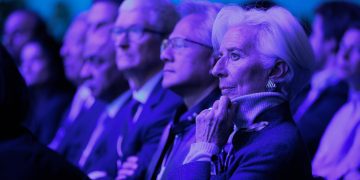 حاضران تیم کوک، جنسن هواهنگ و غیره در یک رویداد رسمی یا کنفرانس با نورپردازی آبی و بنفش، نشسته در ردیف‌های سالن و در حال گوش دادن به سخنرانی یا ارائه