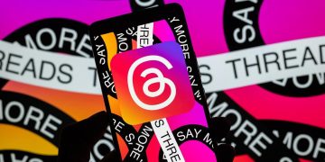 گوشی هوشمند در دست کاربر با نمایش لوگوی شبکه اجتماعی Threads روی صفحه، پس‌زمینه گرافیکی با رنگ‌های گرادیانی و تکرار نام Threads
