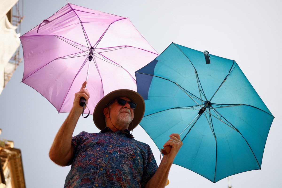 Mike Eggehorn from California uses two umbrellas to shelter from the sun as he queues to enter the Pantheon, during a heatwave across Italy, as temperatures are expected to cool off in the Italian capital, in Rome, Italy July 19, 2023. REUTERS/Guglielmo Mangiapane