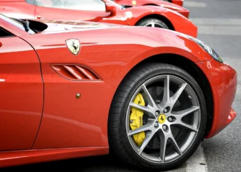 تصویر ردیفی از خودروهای قرمز Ferrari با تمرکز بر رینگ آلیاژی خاکستری و کالیپر ترمز زرد، نماد دقت مهندسی و اصالت برند فراری.