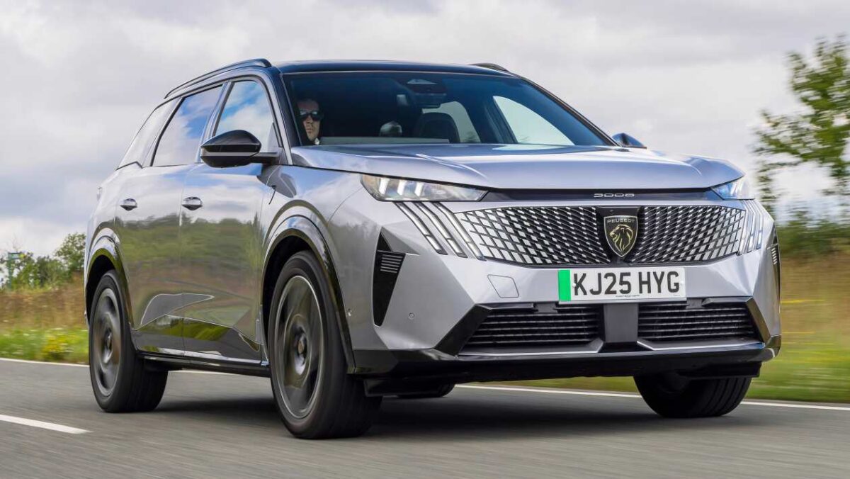 نمای سه‌ربع جلوی پژو E3008 GT Premium آبی‌رنگ در حال حرکت در خیابان، با خطوط بدنه تیز و جلوپنجره مشبک مدرن.