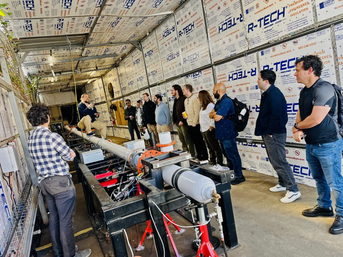 جمع بازدیدکنندگان در کارگاه Longshot کنار لوله آزمایشی کوچکتر