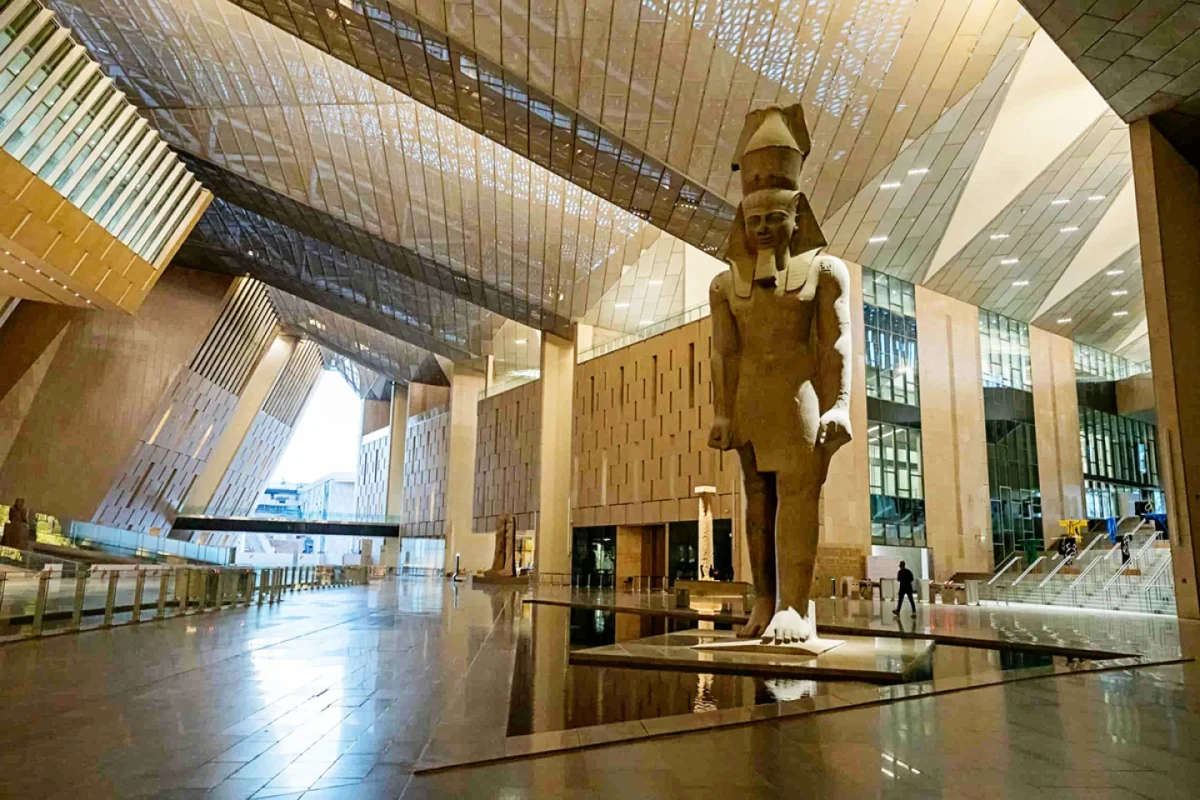 مجسمههای باستانی داخل یکی از گالریهای موزه بزرگ مصر با بازدیدکنندگان در حال تماشا