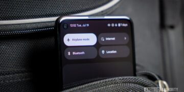 نمای نزدیک از یک گوشی اندروید که دکمه "Airplane mode" در منوی تنظیمات سریع آن فعال است و گوشی در یک جیب یا کیف مشکی قرار دارد.