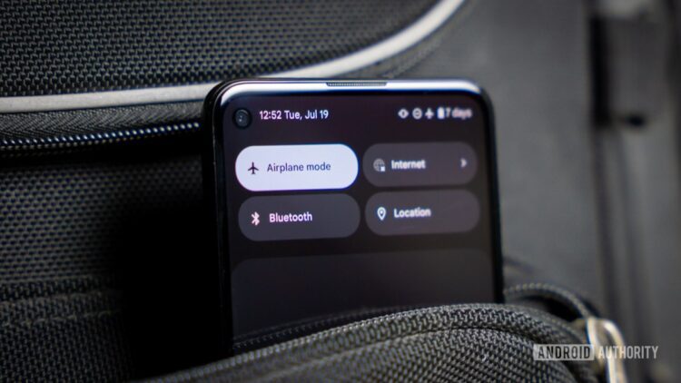نمای نزدیک از یک گوشی اندروید که دکمه "Airplane mode" در منوی تنظیمات سریع آن فعال است و گوشی در یک جیب یا کیف مشکی قرار دارد.