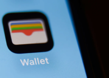 نمای نزدیک از آیکون اپلیکیشن Wallet اپل روی صفحه نمایش یک گوشی با پس‌زمینه آبی روشن.