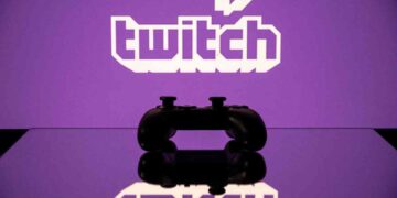 یک کنترلر بازی مشکی که در مقابل لوگوی بنفش Twitch قرار دارد و روی یک سطح براق منعکس شده است.