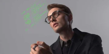 یک مرد جوان در حال استفاده از عینک هوشمند (Smart Glasses) که داده‌های دیجیتالی (ساعت و اطلاعات فهرست) به رنگ نئون سبز را در جلوی چشم او نمایش می‌دهد، و در دستش یک حلقه کنترلر (R1) دارد.