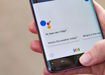 یک گوشی هوشمند که برنامه Google Assistant روی صفحه آن باز است و حبابهای گفتاری "Hi, how can I help?" و "What's the weather today?" دیده میشوند.