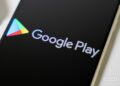 لوگوی Google Play و نام "Google Play" بر روی صفحه نمایش یک گوشی هوشمند با پس‌زمینه مشکی.