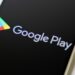 لوگوی Google Play و نام "Google Play" بر روی صفحه نمایش یک گوشی هوشمند با پسزمینه مشکی.