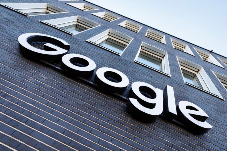 نمای بیرونی یک ساختمان آجری تیره با پنجره&zwnj;های سفید، که لوگوی برجسته و سفید "Google" بر روی آن نصب شده است.