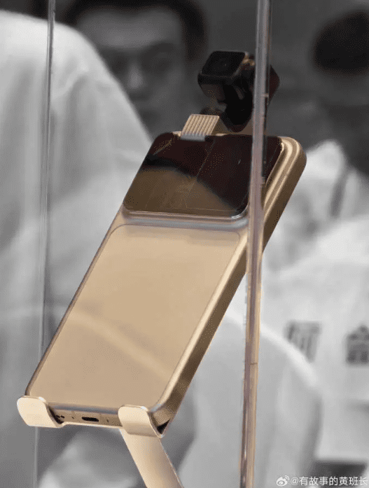 یک نمونه اولیه طلایی رنگ از گوشی "Robot Phone" شرکت Honor در یک قاب محافظ که ماژول دوربین کوچک و قابل چرخش آن در بالا دیده می‌شود.