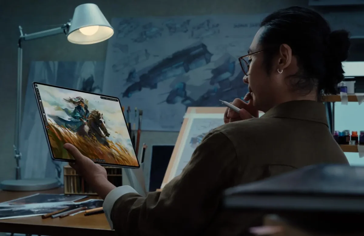 یک مرد در یک استودیوی طراحی با نور کم، در حال نگه داشتن تبلت Huawei MatePad Edge است که یک تصویر هنری دیجیتالی از یک جنگجو روی اسب را نمایش می‌دهد.