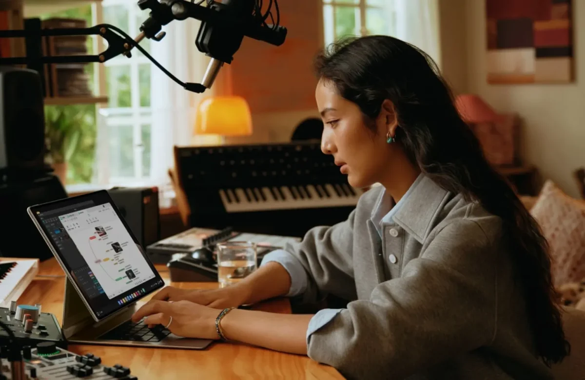 یک زن جوان در یک استودیوی موسیقی خانگی در حال کار با Huawei MatePad Edge متصل به کیبورد است که نرم‌افزار تولید موسیقی را نشان می‌دهد.