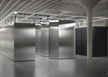 نمای داخلی یک مرکز محاسباتی (احتمالاً کوانتومی) IBM با ردیف‌هایی از محفظه‌های فلزی نقره‌ای بزرگ و بتن خام.