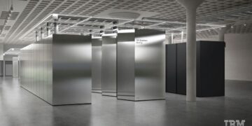 نمای داخلی یک مرکز محاسباتی (احتمالاً کوانتومی) IBM با ردیف‌هایی از محفظه‌های فلزی نقره‌ای بزرگ و بتن خام.