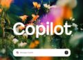 کادر متنی برای ارسال پیام به Copilot در پایین یک تصویر انتزاعی با گل‌ها و نورهای رنگارنگ.