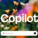 کادر متنی برای ارسال پیام به Copilot در پایین یک تصویر انتزاعی با گل‌ها و نورهای رنگارنگ.