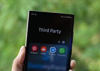 یک گوشی هوشمند که در دست فرد در فضای باز قرار دارد و پوشهای با عنوان "Third Party" و آیکونهای برنامههای پیامرسان (Pinterest, Reddit, Telegram, WhatsApp) در پایین صفحه دیده میشود.