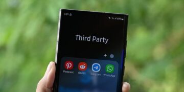 یک گوشی هوشمند که در دست فرد در فضای باز قرار دارد و پوشه‌ای با عنوان "Third Party" و آیکون‌های برنامه‌های پیام‌رسان (Pinterest, Reddit, Telegram, WhatsApp) در پایین صفحه دیده می‌شود.