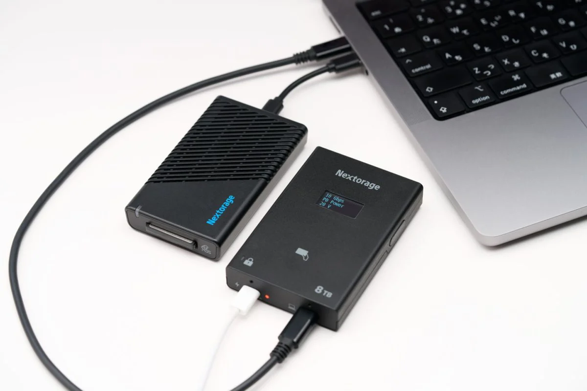 دو اس‌اس‌دی قابل حمل Nextorage در کنار یکدیگر که یکی به یک مک‌بوک متصل است و نمایشگر کوچک آن در حال نمایش سرعت انتقال ۱۰ گیگابیت بر ثانیه و برق رسانی (PD power) است.