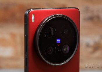نمای نزدیک از ماژول دوربین پشتی یک گوشی هوشمند قرمز رنگ (احتمالاً Vivo X100 Pro) با چهار لنز و برند ZEISS در یک ماژول دایرهای بزرگ.