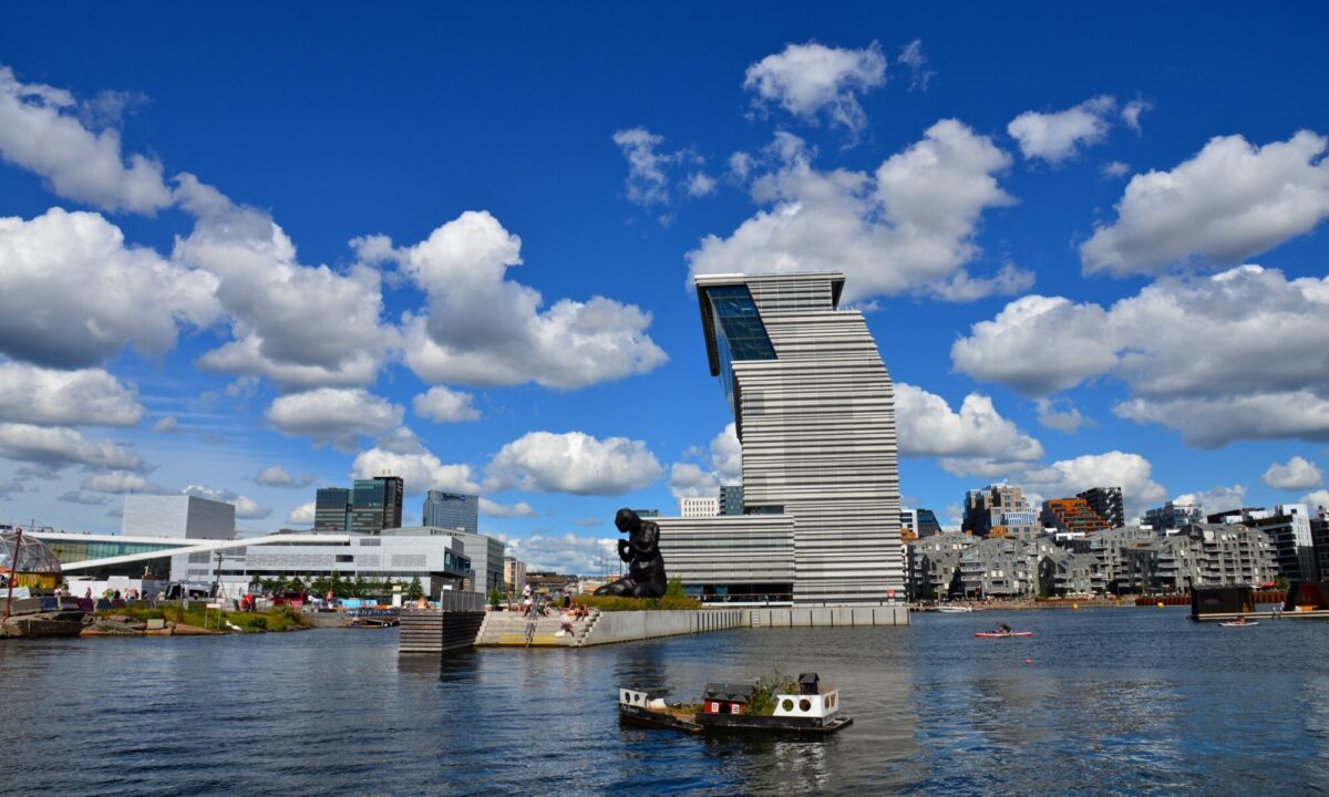 ساحل شهر اسلو با ساختمان‌های مدرن و مجسمه‌ی کنار آب