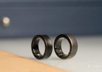 دو حلقه هوشمند Oura Ring مشکی رنگ که از نمای نزدیک کنار هم روی یک سطح براق قرار دارند.