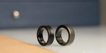 دو حلقه هوشمند Oura Ring مشکی رنگ که از نمای نزدیک کنار هم روی یک سطح براق قرار دارند.