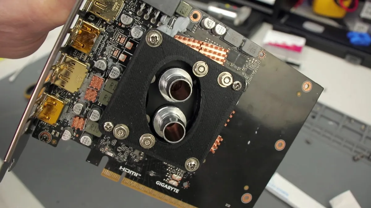 نمای نزدیک از یک کارت گرافیک کوچک Gigabyte RTX با مدار چاپی (PCB) سیاه، که یک بلوک خنککننده آب سفارشی با ورودیهای لولهای در مرکز آن قرار دارد.