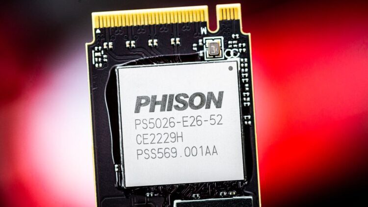 نمای نزدیک از یک تراشه کنترلر SSD با مارک "PHISON" و شماره مدل "PS5026-E26-52" بر روی یک برد مدار چاپی (PCB) با پس‌زمینه قرمز مات.