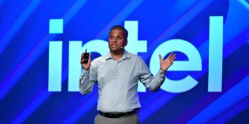 ساچین کاتی در حال سخنرانی روی صحنه و ژست بازوهای باز، با لوگوی بزرگ "intel" با پس‌زمینه آبی روشن.