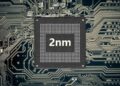 یک تراشه نیمهرسانا (Semiconductor chip) با متن بزرگ "2nm" در وسط، که بر روی یک برد مدار چاپی (PCB) با بافت شبکه سیاه و سفید قرار دارد.