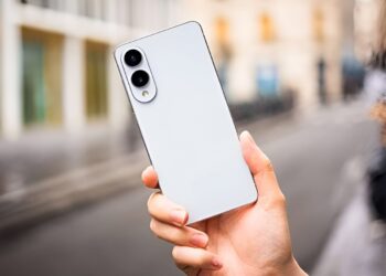 گوشی هوشمند سفید رنگ Samsung Galaxy S26 Series از نمای پشت که در دست فردی در محیطی شهری و کمی مه‌آلود نگه داشته شده و دارای دو لنز دوربین عمودی است.