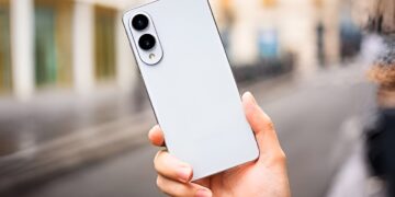 گوشی هوشمند سفید رنگ Samsung Galaxy S26 Series از نمای پشت که در دست فردی در محیطی شهری و کمی مه‌آلود نگه داشته شده و دارای دو لنز دوربین عمودی است.