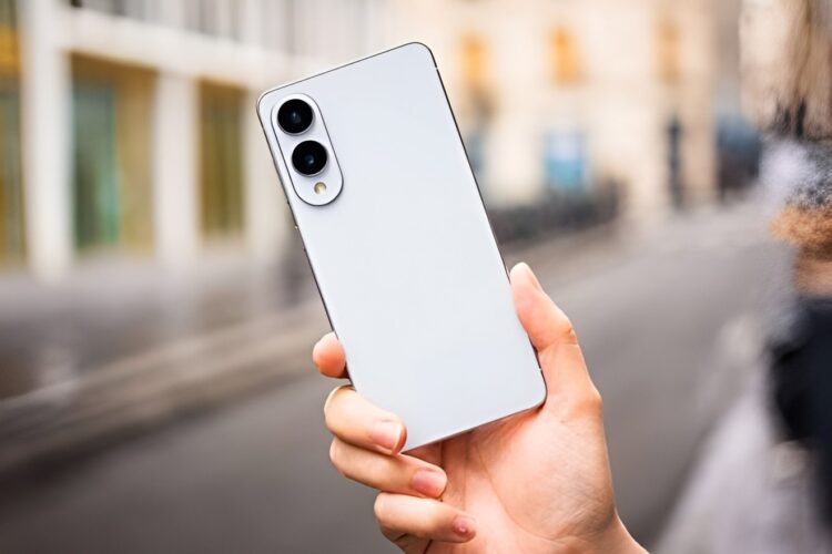 گوشی هوشمند سفید رنگ Samsung Galaxy S26 Series از نمای پشت که در دست فردی در محیطی شهری و کمی مه‌آلود نگه داشته شده و دارای دو لنز دوربین عمودی است.