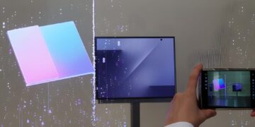 نمایشگر تاشو سامسونگ که یک مکعب سهلتهای رنگارنگ (صورتی و آبی) را نمایش میدهد و یک فرد با گوشی خود در حال عکاسی از آن است.