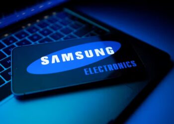 یک کارت که لوگوی "SAMSUNG ELECTRONICS" بر روی صفحه آن دیده می‌شود و روی یک صفحه کلید لپ‌تاپ در محیطی با نورپردازی آبی تاریک قرار دارد.