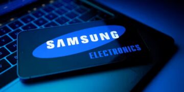یک کارت که لوگوی "SAMSUNG ELECTRONICS" بر روی صفحه آن دیده می‌شود و روی یک صفحه کلید لپ‌تاپ در محیطی با نورپردازی آبی تاریک قرار دارد.