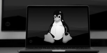 لپ‌تاپی که توکس (Tux)، نماد لینوکس، را در یک پس‌زمینه سیاه و سفید نمایش می‌دهد، نمادی از لغو تولید لپ‌تاپ Snapdragon X1 Elite با لینوکس.