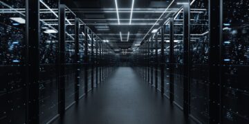 یک راهرو طولانی و تاریک در یک مرکز داده (Data Center) با ردیف‌هایی از رک‌های سرور روشن با نورهای آبی نئونی.