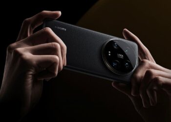 نمای پشت گوشی Xiaomi با بافت چرمی سیاه و ماژول دوربین بزرگ دایرهای Leica، که توسط دو دست در حالت افقی نگه داشته شده است.