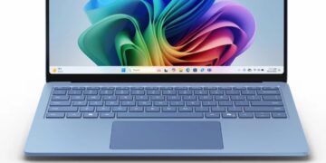 نمای جلو لپ‌تاپ آبی رنگی که ویندوز ۱۱ را با پس‌زمینه رنگین‌کمانی روشن نمایش می‌دهد.