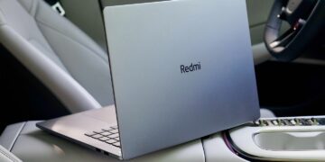 لپ‌تاپ Redmi با در باز در داخل یک ماشین، که لوگوی Redmi روی درب نقره‌ای آن دیده می‌شود.