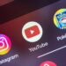 لوگوهای برنامه YouTube، Instagram و Pokemon TCG Live روی صفحه اصلی یک گوشی هوشمند.