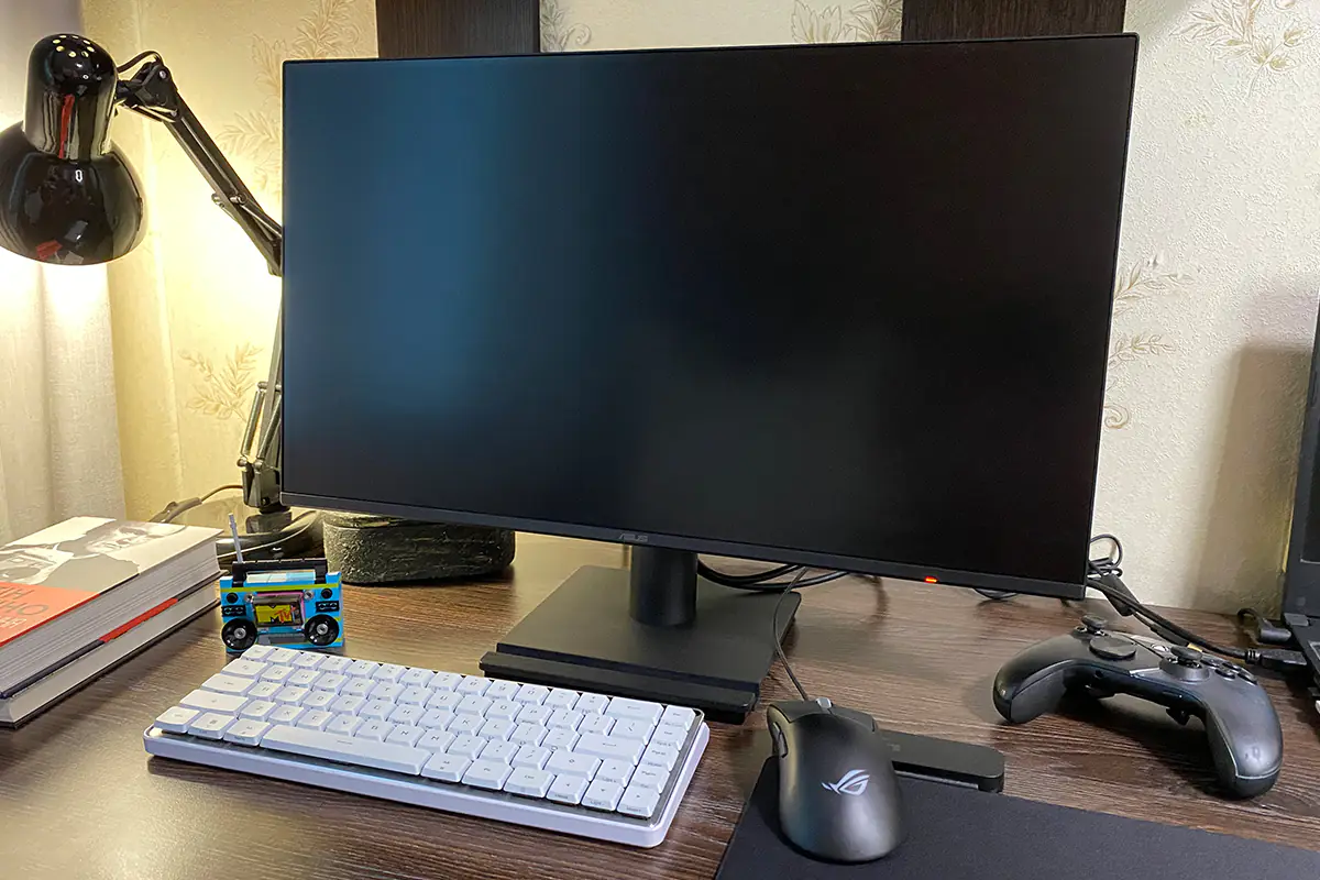 مانیتور VA259HGA ایسوس روی یک میز در کنار کیبورد، ماوس، کنترلر بازی و باقی لوازم
